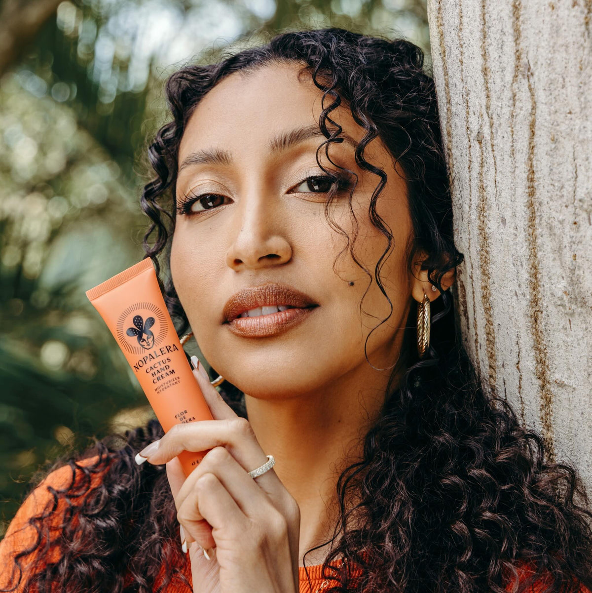 Woman holding a tube of Nopalera  Flor de Madera hand cream in a natural setting