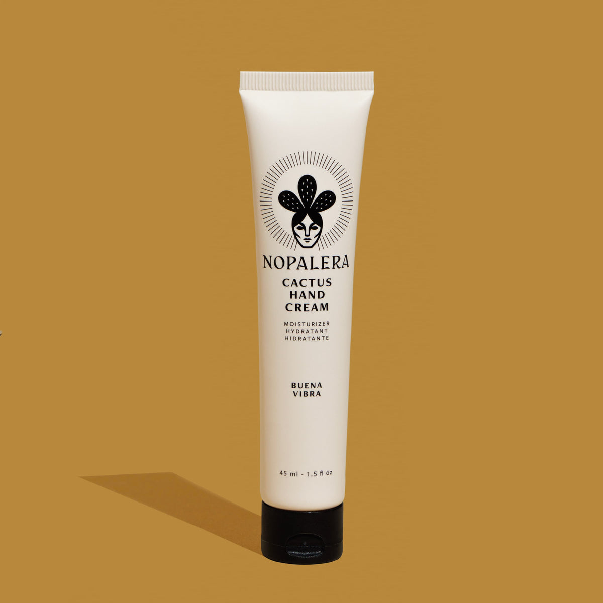 A single tube of Nopalera Cactus Hand Cream in 'Buena Vibra' scent, standing upright on a solid mustard-yellow background with a soft shadow cast to the left.