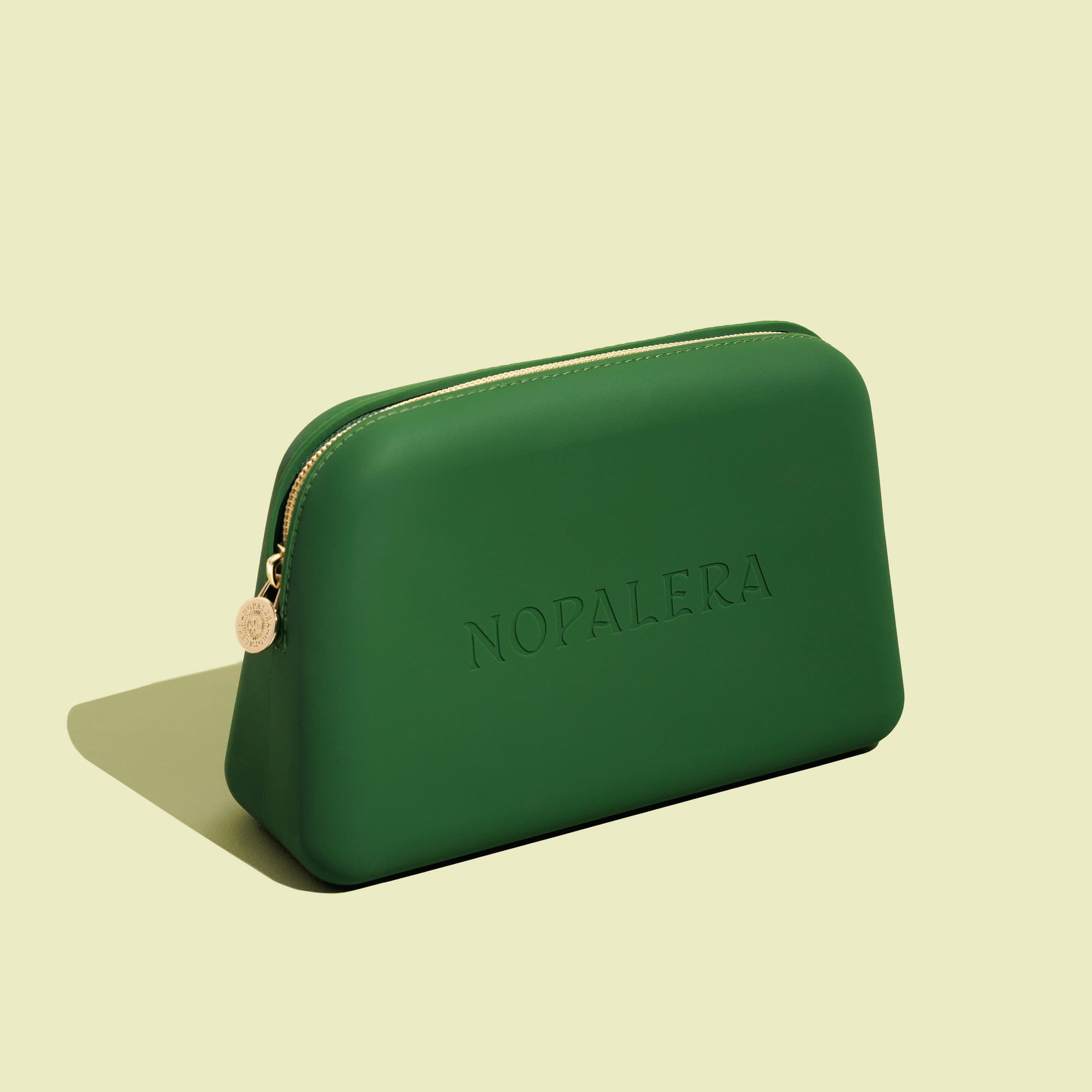 Green nopalera.sbssmetic pouch with gold zipper and embossed logo on a neutral background.