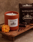 Nopalera scented candle with packaging on a wooden tray against a brown background