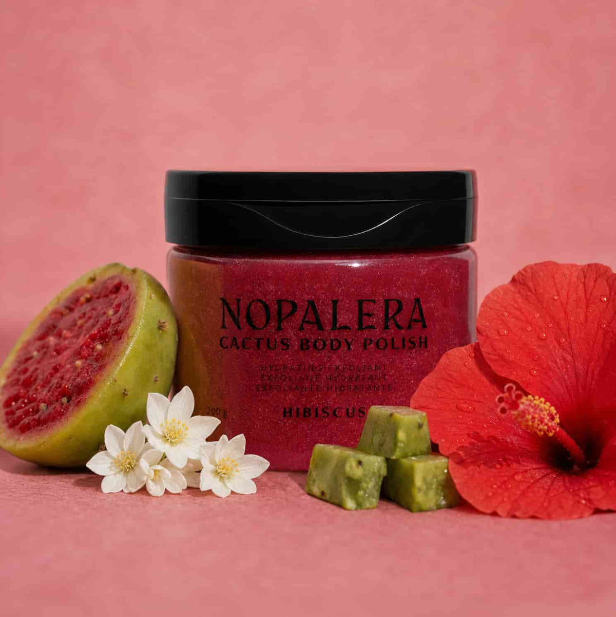 Nopalera cactus body polish jar with guava, flowers, and hibiscus on a pink background